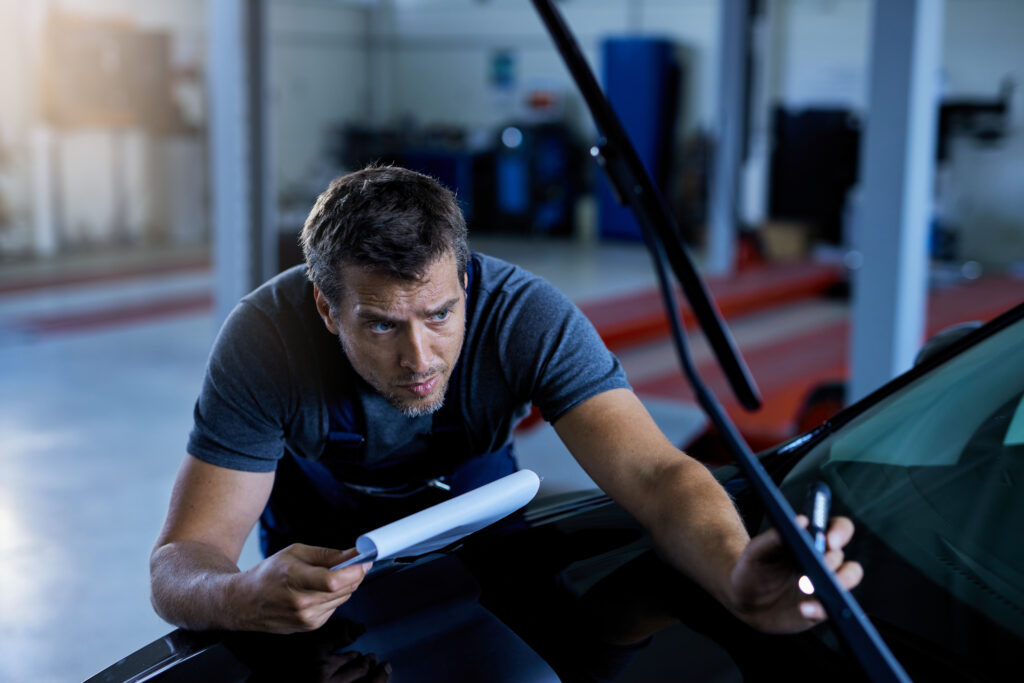 car mechanic examining vehicle problems while working auto repair shop scaled