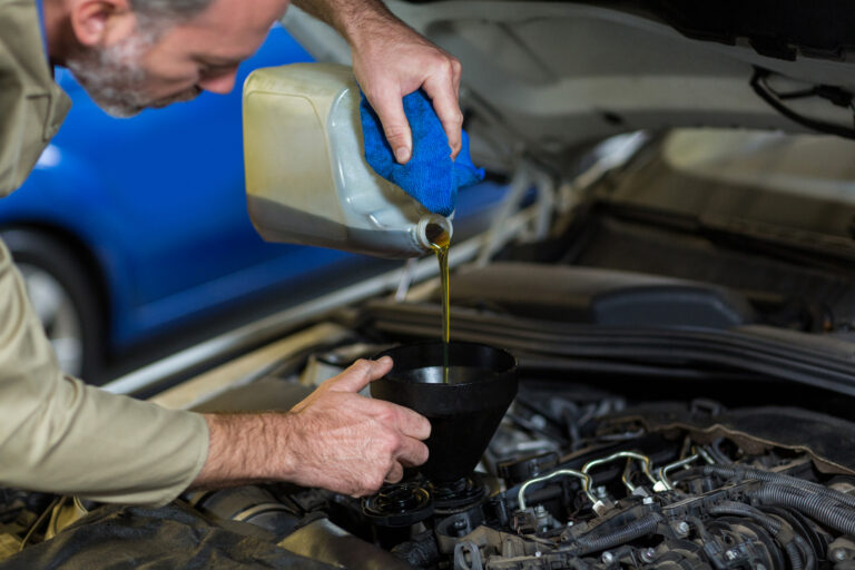 mechanic pouring oil into car engine scaled